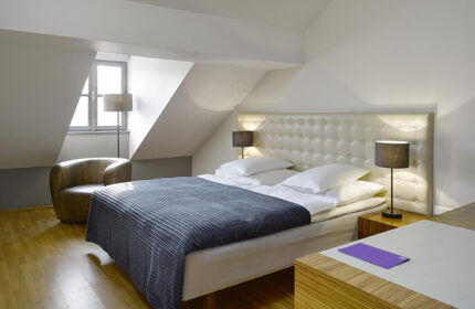 Cool trendy design at The Icon Hotel and Lounge, Prague city center. A modern room with a double bed, chair and lamps. Gay-friendly hotel.