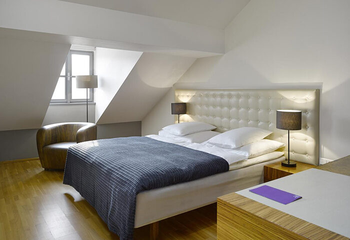 Cool trendy design at The Icon Hotel and Lounge, Prague city center. A modern room with a double bed, chair and lamps. Gay-friendly hotel.