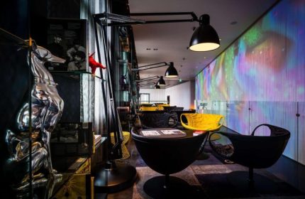 art'otel Amsterdam lobby with modern design, colorful wall art, stylish chairs, and unique art pieces. Coolest art hotel near gay area.