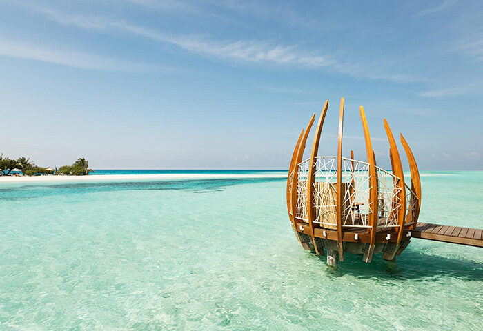 LUX* South Ari Atoll: Coolest gay beach bar in Maldives. Overwater structure with seating, turquoise water, and blue sky. Gay travel.