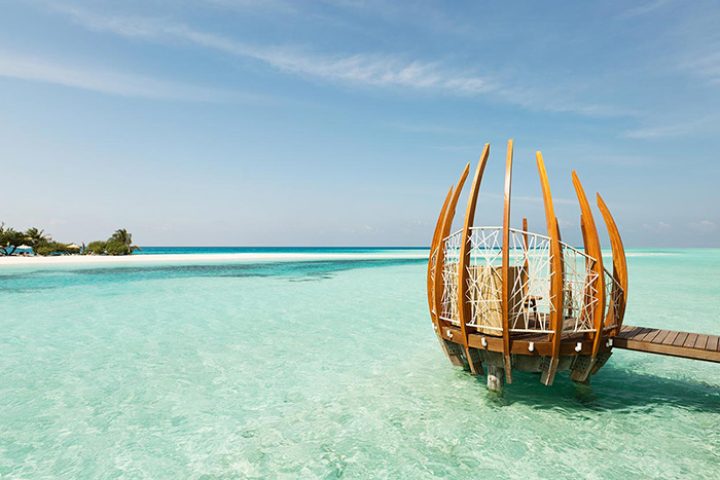 LUX* South Ari Atoll: Coolest gay beach bar in Maldives. Overwater structure with seating, turquoise water, and blue sky. Gay travel.