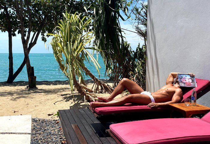 Gay man relaxing at W Koh Samui hotel beach. Coolest gay beach hotels and pool villas in Koh Samui, Thailand. Travel advice for gay men.