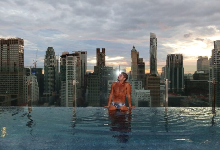 Gay traveler at Hotel Indigo Bangkok Wireless Road rooftop pool. Coolest Bangkok hotels for gay men. Bangkok skyline view.