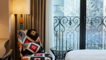 Burdock Hotel Istanbul, Autograph Collection room. Patterned chair, lamp, and balcony view. Coolest gay hotels Istanbul offer stylish stays.