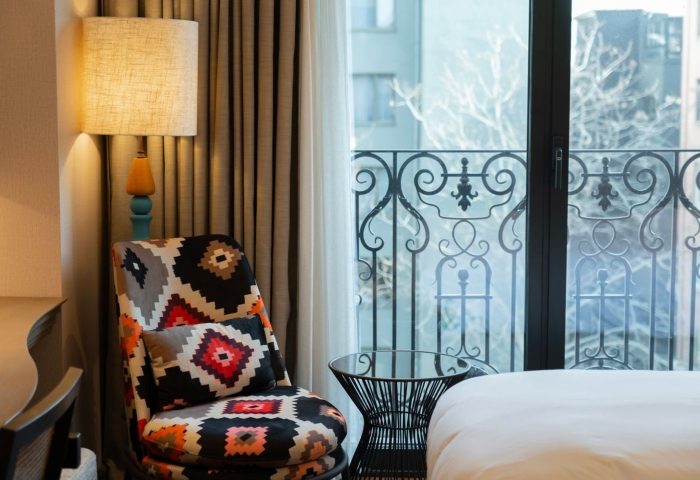 Burdock Hotel Istanbul, Autograph Collection room. Patterned chair, lamp, and balcony view. Coolest gay hotels Istanbul offer stylish stays.