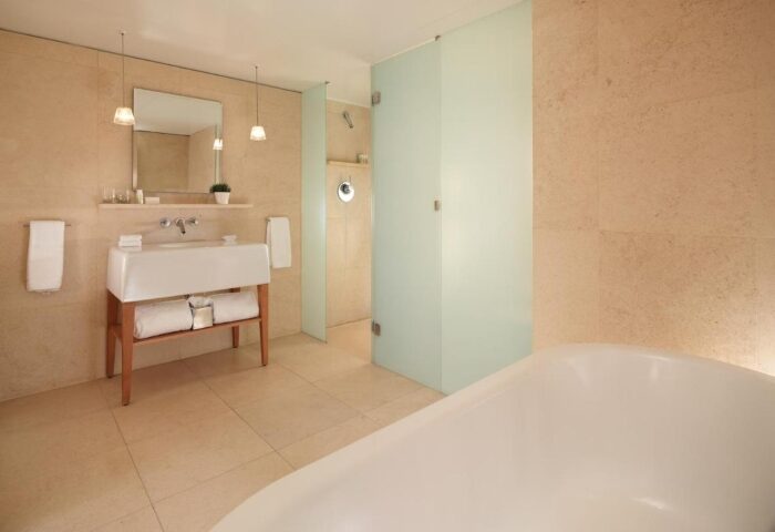 St Martins Lane Hotel London bathroom. Modern design with white sink, shower, and tub. Coolest gay hotels in London city center Soho.