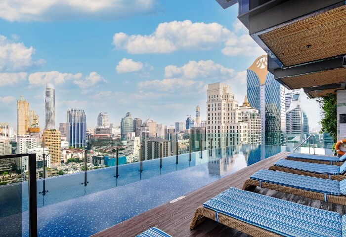 Coolest Rooftop Pool at Hotel Indigo Bangkok Wireless Road, a gay-friendly hotel. Skyline view from the pool deck with lounge chairs.