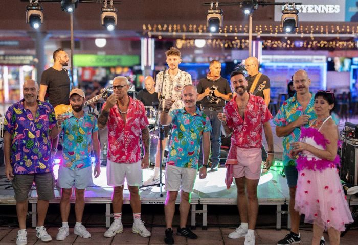 Live band at Copacabana Gay Bar in Gran Canaria. Group of men and a woman in colorful shirts and shorts perform on stage. Gay travel.