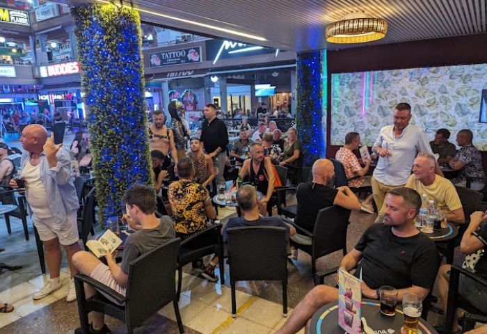 Copacabana Gay Bar in Gran Canaria. Men gather at the gay bar, enjoying drinks and conversation in the vibrant, open-air setting.