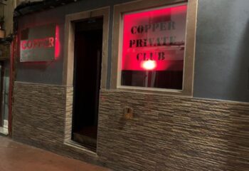 Copper Private Club in Benidorm, a gay cruising location. Red neon sign illuminates the entrance, promising a discreet and exciting experience.