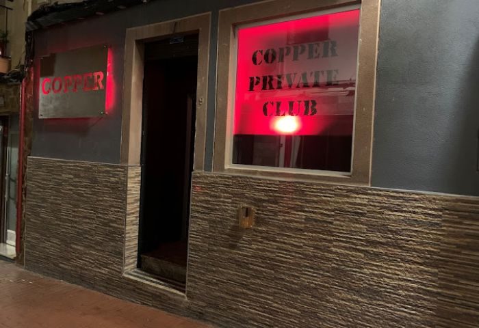 Copper Private Club in Benidorm, a gay cruising location. Red neon sign illuminates the entrance, promising a discreet and exciting experience.