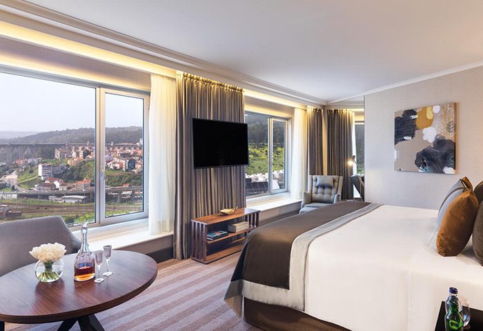 Corinthia Hotel Lisbon room with city view. Luxury gay hotel in city center. Modern design, comfortable bed, and large windows. Perfect for gay travel.