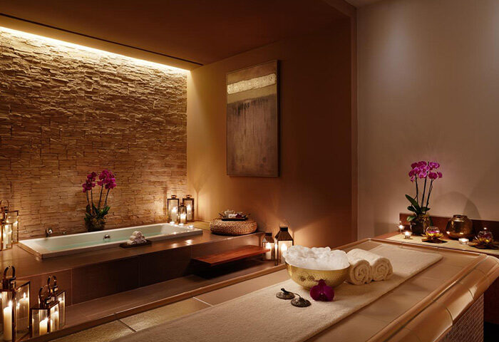 Corinthia Hotel Lisbon spa: Bathtub and massage table, candles, and flowers create a relaxing wellness atmosphere. Best in Lisbon for relaxation.