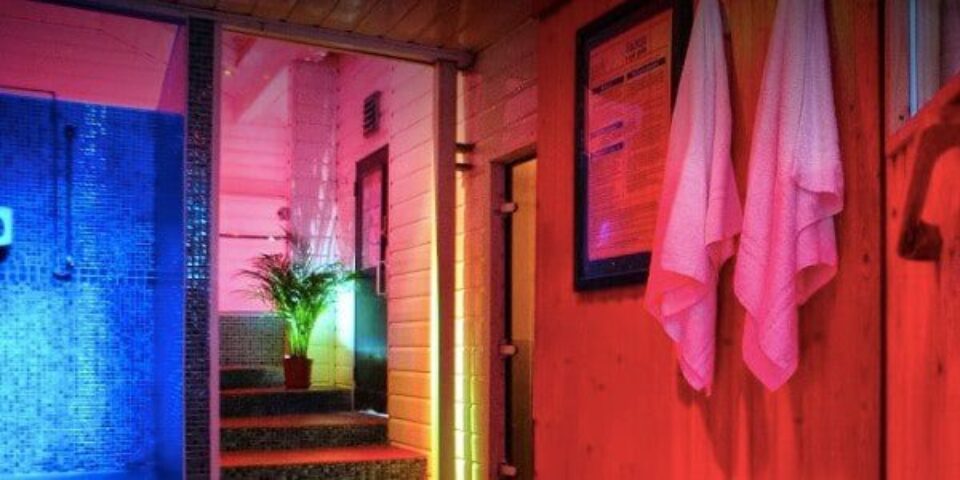 Covent Garden Health Spa gay sauna. Interior view with towels, plant, and blue-tiled shower. A relaxing space for gay men's travel in London.