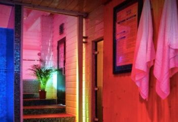 Covent Garden Health Spa gay sauna. Interior view with towels, plant, and blue-tiled shower. A relaxing space for gay men's travel in London.