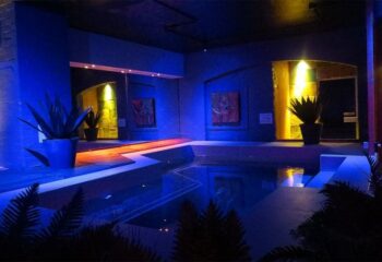 Covent Garden Health Spa gay sauna. Interior of a gay sauna with a pool, blue lighting, plants, and artwork. Gay travel and health.