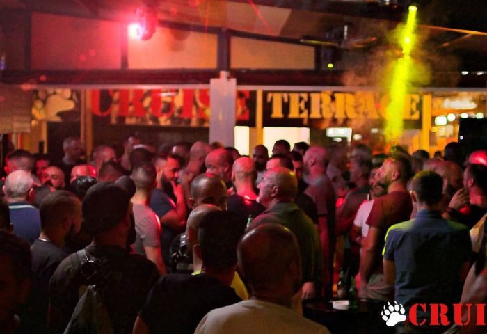 Inside Cruise Bar, a popular gay cruise club in Gran Canaria. A crowd of men mingle under red and yellow lights, enjoying the vibrant nightlife.