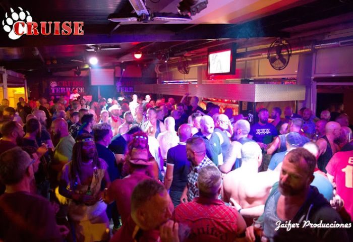 Cruise Bar Gran Canaria: A crowded, dimly lit gay cruise club with men dancing and socializing on the terrace. Nightlife scene.