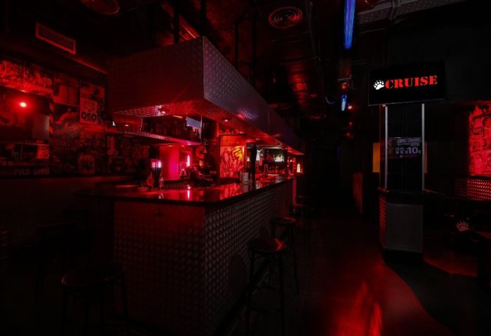 Interior of Cruise Bar, a gay cruise club in Gran Canaria, featuring a bar, stools, and red lighting, popular for gay nightlife.