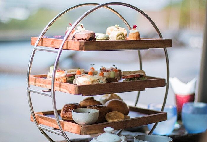 Afternoon tea at luxury Chiang Mai riverside resort. Three-tiered stand with cakes, sandwiches, and scones. Gay travel Thailand.