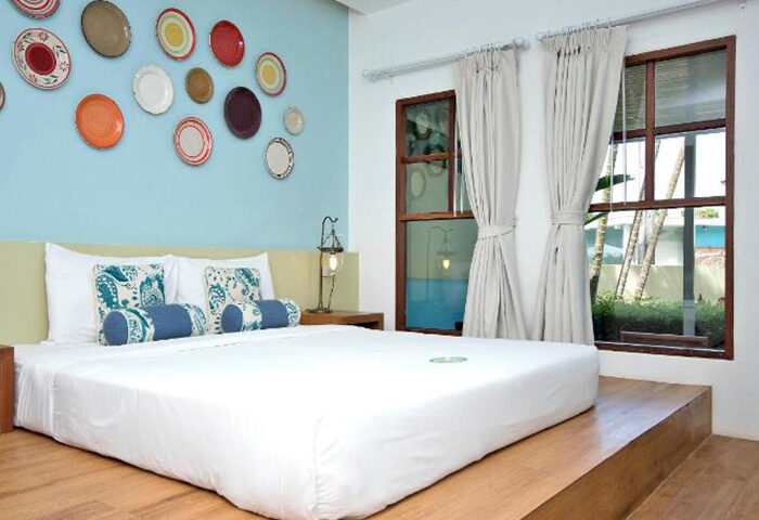Samed Club Resort cute beachfront hotel Koh Samet for gay honeymoon couples. Bedroom with plates on the wall and windows with curtains.