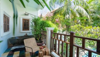 Balcony view at Rambutan Resort, a cute gay hotel in Siem Reap. Stone tub, chair, & fruit. Lush greenery. Ideal for gay travel.