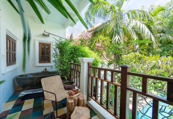 Balcony view at Rambutan Resort, a cute gay hotel in Siem Reap. Stone tub, chair, & fruit. Lush greenery. Ideal for gay travel.