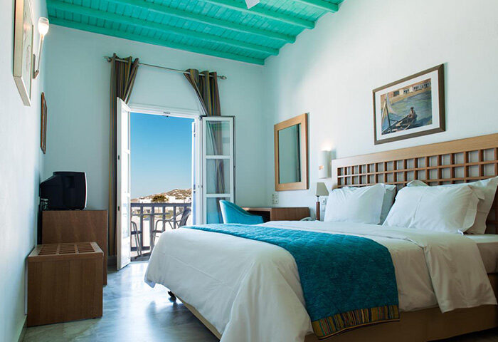 Poseidon Hotel Suites room in Mykonos Town (Chora). Private balcony with a view. Gay hotel room with blue ceiling and bedspread.