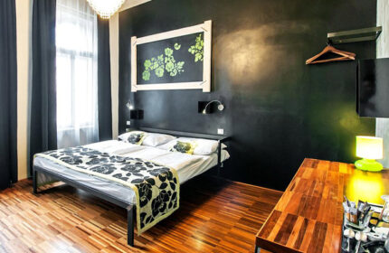 Czech Inn, best gay hostel in Prague. Room interior: bed with floral cover, dark wall, wooden floor. Gayborhood Vinohrady for solo gay travelers.