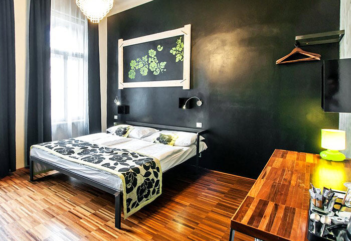 Czech Inn, best gay hostel in Prague. Room interior: bed with floral cover, dark wall, wooden floor. Gayborhood Vinohrady for solo gay travelers.