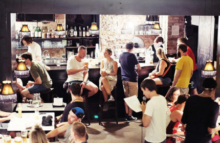 Czech Inn, a gay-friendly party hostel. People at the bar, enjoying drinks. Best gayborhood hostel for gay travelers in Prague.