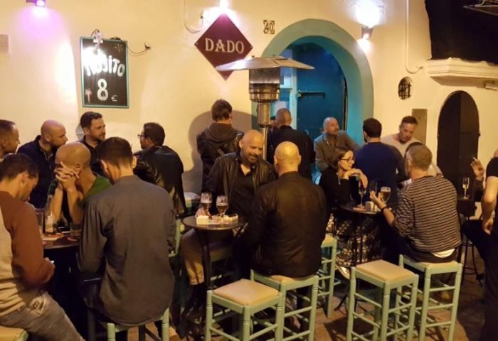 Dado Bar, a gay bar in Ibiza. People drinking at tables. Nightlife scene. Gay travel. Ibiza gay bar. Drinks and socializing.