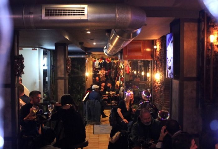 Mystic Gay Bar in Madrid: Interior view of patrons enjoying drinks in a warmly lit, atmospheric gay bar in Madrid, Spain.