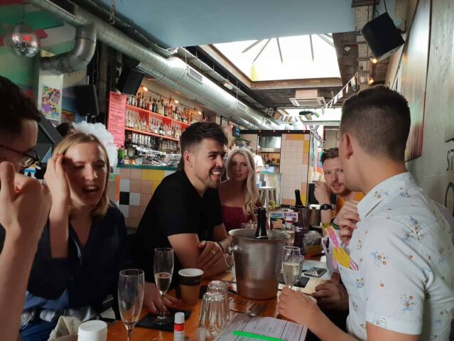 Dalston Superstore gay bar: A group of friends at a table, drinking champagne. Popular gay venue in London's Dalston area.