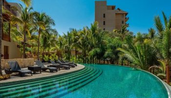 Delta Hotels by Marriott Riviera Nayarit All-Inclusive pool view. Gay travel luxury resort with palm trees and lounge chairs for relaxation.