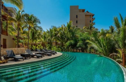 Delta Hotels by Marriott Riviera Nayarit All-Inclusive pool view. Gay travel luxury resort with palm trees and lounge chairs for relaxation.