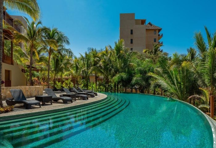 Delta Hotels by Marriott Riviera Nayarit All-Inclusive pool view. Gay travel luxury resort with palm trees and lounge chairs for relaxation.