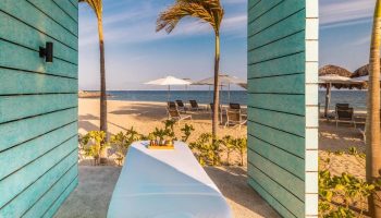 Delta Hotels Riviera Nayarit All-Inclusive: Massage table with beach view. Gay travel to Mexico for relaxation and pampering. Palm trees, sand.