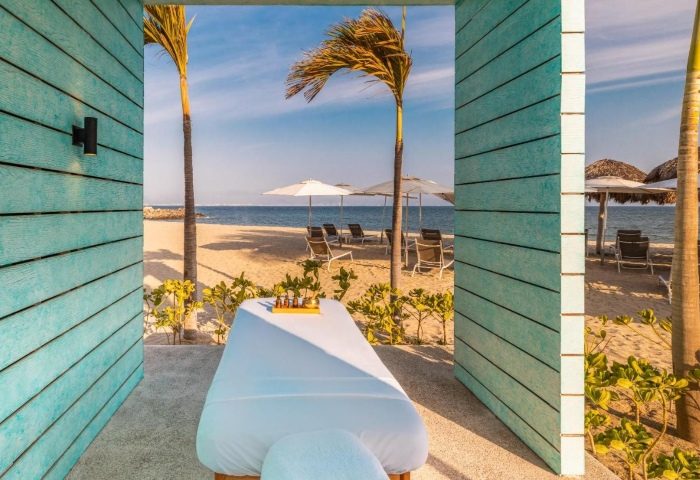 Delta Hotels Riviera Nayarit All-Inclusive: Massage table with beach view. Gay travel to Mexico for relaxation and pampering. Palm trees, sand.