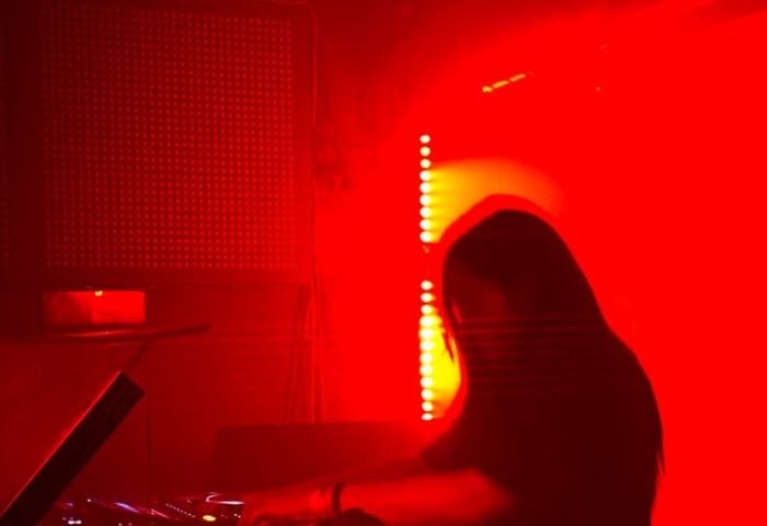 DJ at Dirty Cash Budapest, a gay nightlife spot. Red lighting, silhouette of a person mixing music. Gay travel in Budapest.