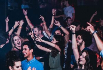 Crowd of people dancing at Disco City Hall, a gay club in Barcelona. People are smiling and have their hands in the air. Nightlife scene.