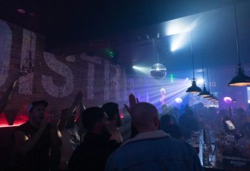 District Video Lounge, a gay bar in Montreal. Crowd of gay men enjoying the nightlife, with disco ball and bar. Gay travel.