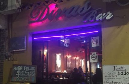 Diva's Gay Bar in Puerto Vallarta. Exterior view with neon sign, happy hour specials, and patrons inside. A popular gay travel destination.