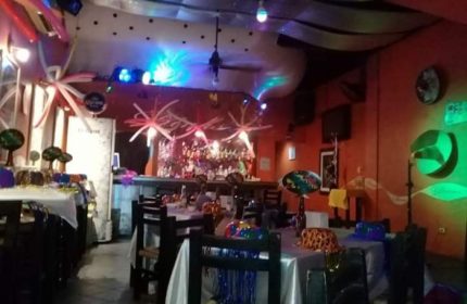 Diva's Gay Bar in Puerto Vallarta. Interior view of the bar with tables, chairs, decorations, and a bar in the background. Nightlife.