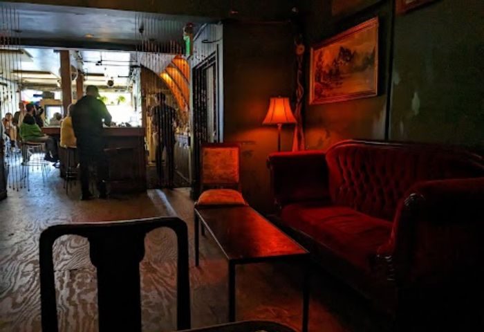 Interior of Driftwood Bar in San Francisco, a gay-friendly travel destination. Red velvet couch and dim lighting create a cozy, intimate atmosphere.