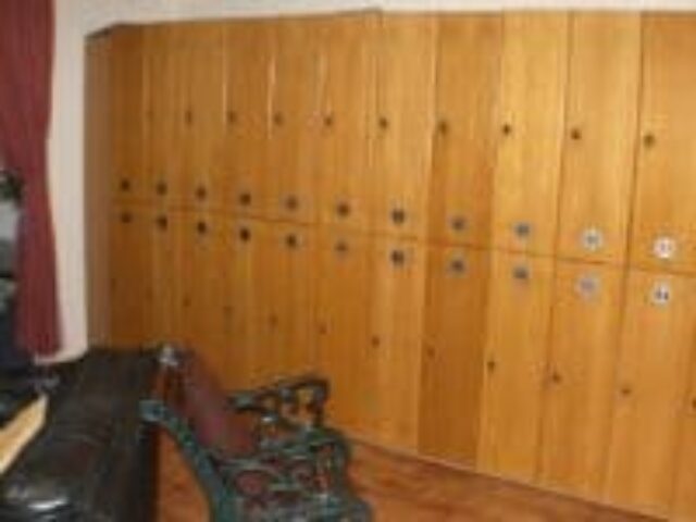 Lockers at E15 Club, a gay sauna. Wooden lockers line the wall, offering secure storage. Seating area visible. Gay travel advice.