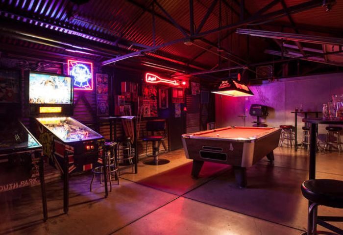 EAGLE LA: Bar interior featuring pinball machines, pool table, & neon signs. A popular gay bar in Los Angeles known for its laid-back atmosphere.