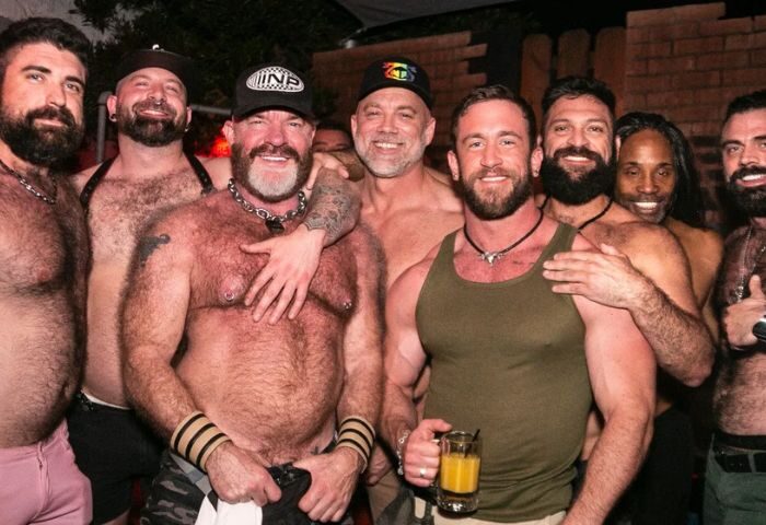 EAGLE LA experience: Group of gay men, some shirtless, at EAGLE LA bar. Bearded men smiling, enjoying the gay nightlife. Gay travel advice.