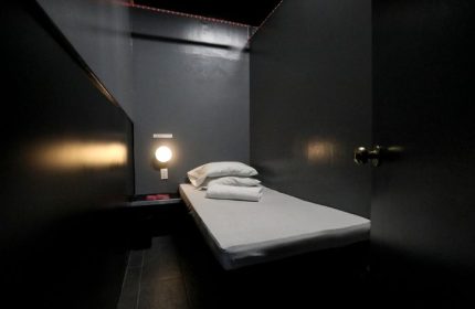 East Side Club, New York gay sauna. Private room with bed, pillows, towels, and dim lighting. A dark, intimate space for relaxation.