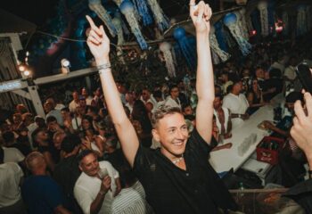 Eden Beach Club gay bar in Torremolinos: Man with raised arms at a party. Gay nightlife, gay travel destination, Spain. Crowd, bar.